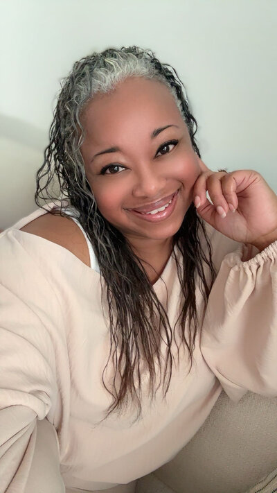 Letitia Hopkins, Main Character Energy mentor, warm headshot on a couch with a confident, welcoming smile.