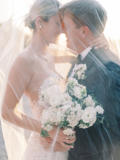 A breathtaking golden hour wedding portrait with the bride and groom under the veil. Captured in fine art wedding photography for a timeless, intimate moment.