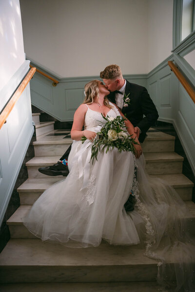 Bride and groom have a quiet moment in a staircase on their wedding day.