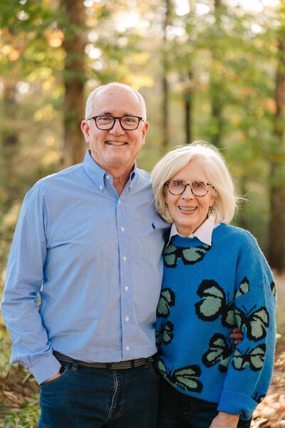 David Munsey Jr. and Ruth Ann Munsey, founders of Better Lawns and Gardens, smiling outdoors in a wooded area in Little Rock, Arkansas.