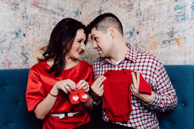 Maternity Photoshoot: Couple holding baby clothes