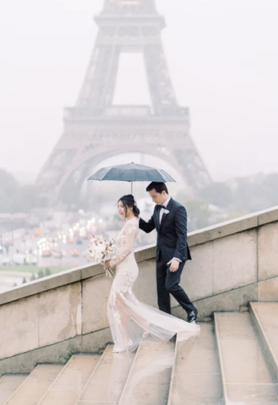 Paris elopement photo with bride and groom under umbrella at Eiffel Tower