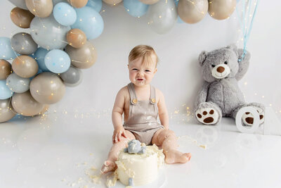 Little boy wearing a grey jumper for his teddy bear cake smash photos.