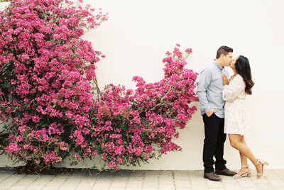 couple kissing in front of bouganvillea