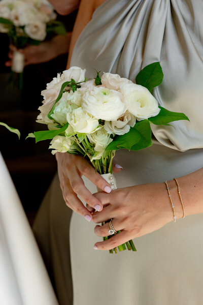 woman in taupe dress holding a small flower bouquet