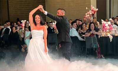 Bride and groom sharing a first dance on a cloud-like floor surrounded by seated wedding guests