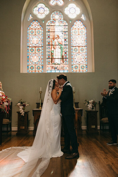 bride and groom sharing their first kiss at the alter of a church