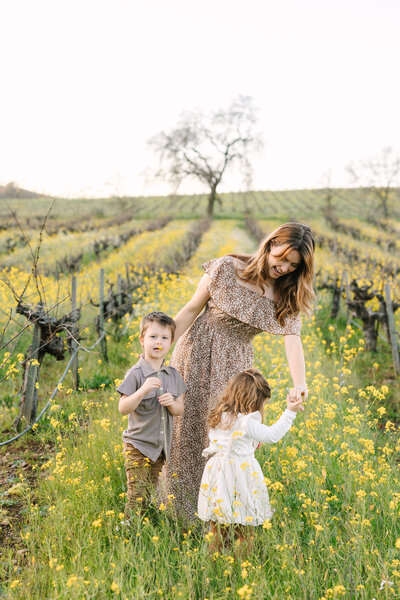 mom dancing with her kids in a field of mustard flowers