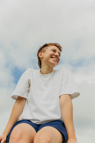 Teenager smiling in front of clouds