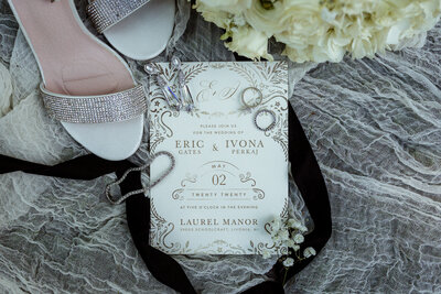 Close up of brides wedding shoes with rings and invitation