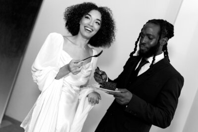 Black and white photo of joyful couple eating cake at their Phoenix wedding reception.