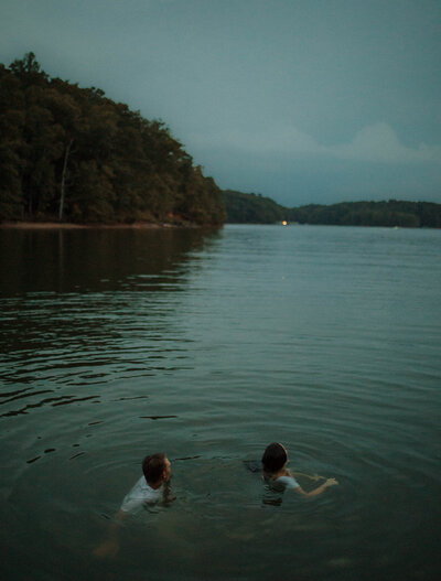 couple swimming in the water together during blue hour