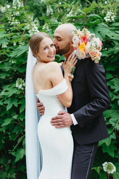 Close-up of a wedding bride and groom with greenery, photographed by Joy and Light Photography at Crystal Bridges in Bentonville, Arkansas.