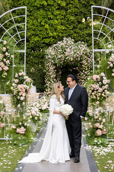 A bride and groom hugging and standing in the middle of an aisle