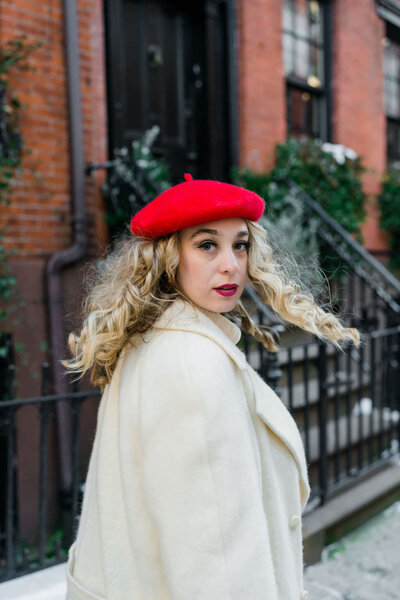 woman in a red hat walking down the street and looking back over her shoulder