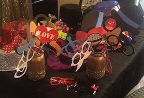 Expect to see a a black cloth covered table with a wide variety of photo booth props to be enjoyed by all guests.