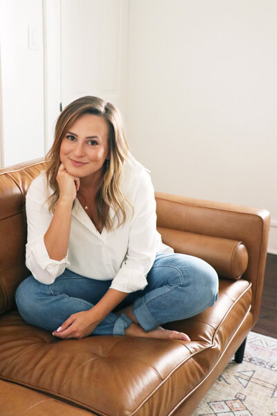 woman sitting on leather couch in white shirt and jeans