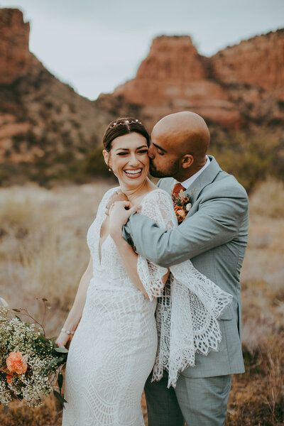bride and groom standing in front of sedona backdrop