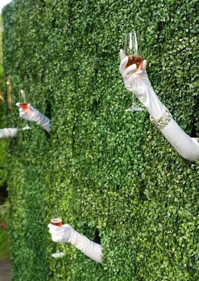 Guests arriving through greenery at a garden-inspired Hamptons fundraiser