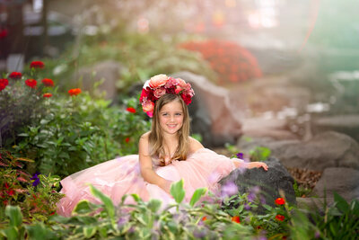 Girl sitting in lush flowers in ball gown