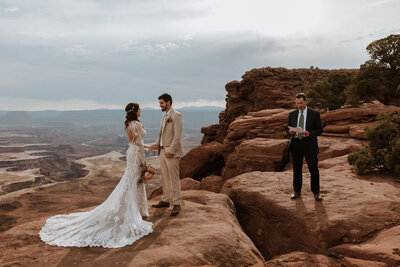 bride and groom standing in the desert with their officiant