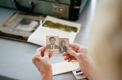 an elderly woman holding a photo of her husband and herself in his hands. 