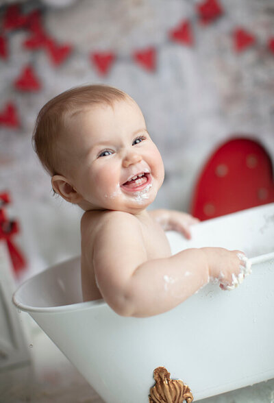 Baby laughing in tub at her Dallas cake smash.