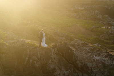 Dramatic cliffs serve as the location for bride and groom to stand on for their ceremony