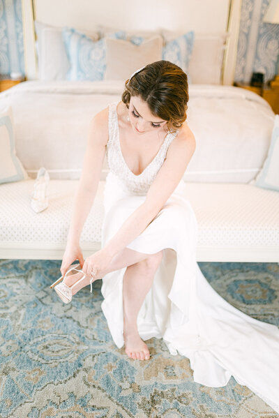 Beautiful bride wearing wedding dress puts on her heels
