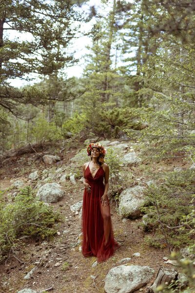 woman with a flower crown and a red dress standing in the forest