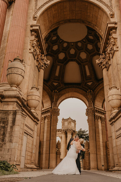 newlyweds kiss under arch