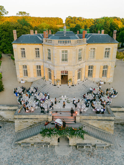 Luxury destination wedding reception at a French château with guests dining outdoors, photographed by Thomas Raboteur, destination wedding photographer