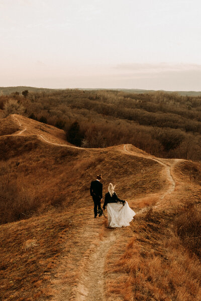 Bride and groom walk across Loess Hills