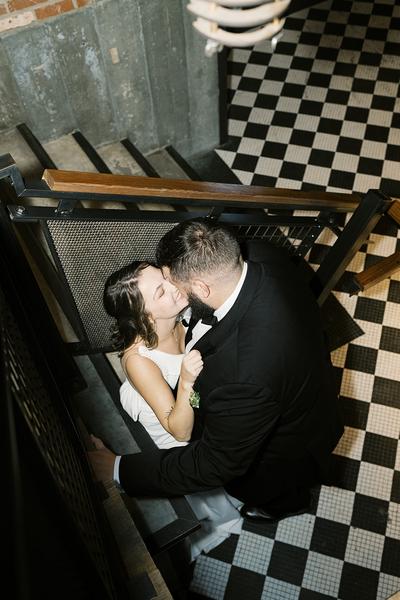 Newlywed's kissing behind the staircase at their wedding reception | Megan Smith Photography