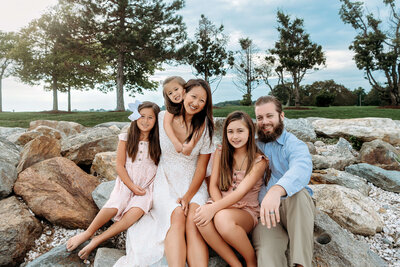Family of five sitting on rocks during a beach photo session at Sherwood Island in Westport, CT