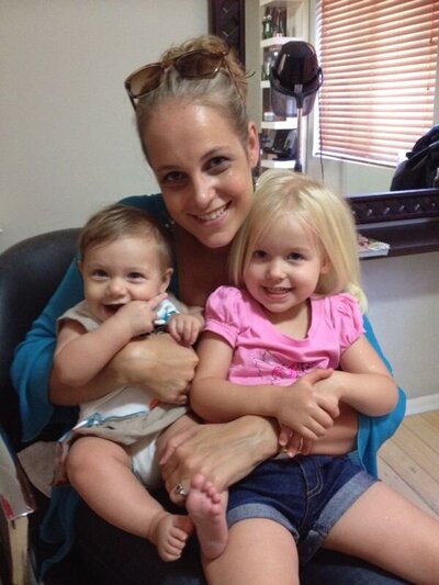 Salome sitting with her two daughters  on her lap at a hair salon