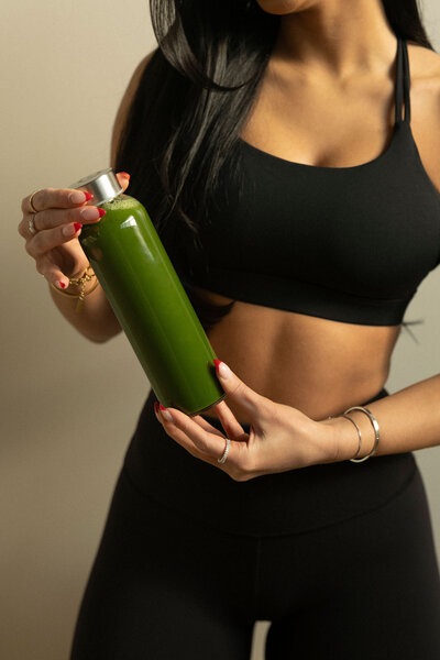 Client holding a green smoothie, representing a healthy lifestyle supported by EMS membership options.