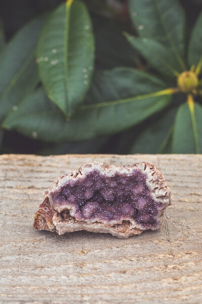 Purple amethyst crystal on a wooden platform.