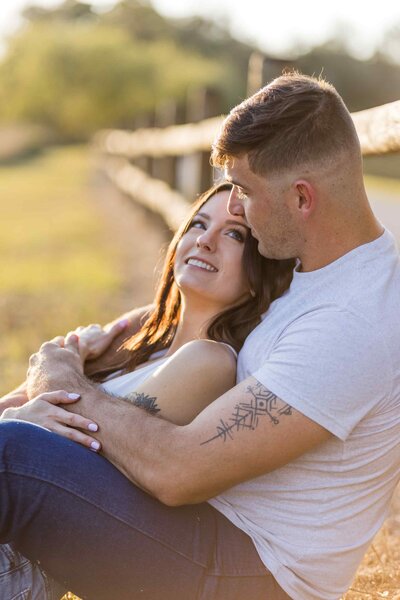A man holding his fiance in a field at golden hour