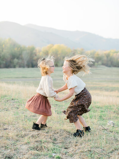 two little girls jumping up and down in a field