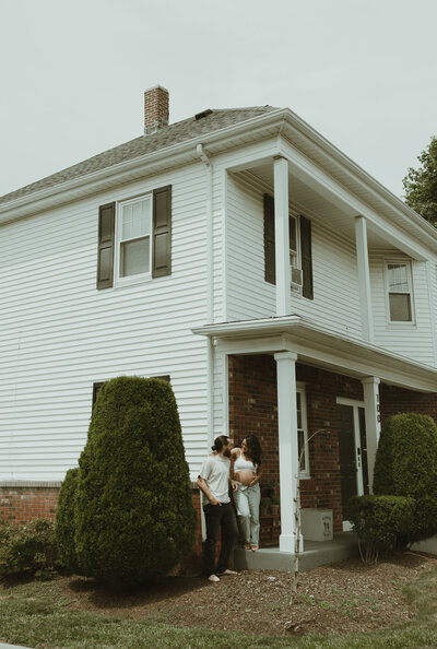 Pregnant woman laughs and holds a cup of coffee in her kitchen for maternity photos