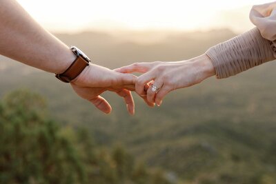 romantic close up photo of two hands reaching for each other in mountains