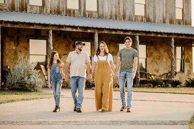 candid family portrait of family walking together in front of the El Cerrito Lodge Wedding and Event Venue in East Texas