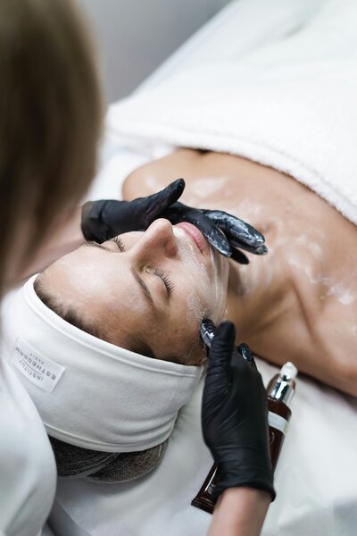 Esthetician applying facial treatment at Maven + Grace Salon in McMinnville, Oregon, highlighting expert skincare services