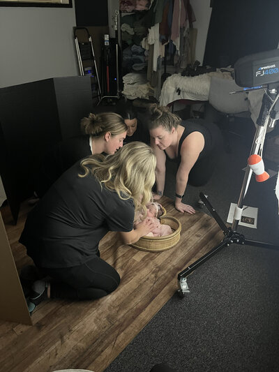 wrapping baby in blue wrap during professional newborn photography session in Grand Rapids studio