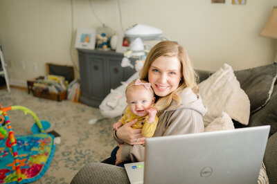 Erika holding her daughter while sitting in front of her laptop