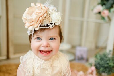 Baby girl smiles with large floral headband.
