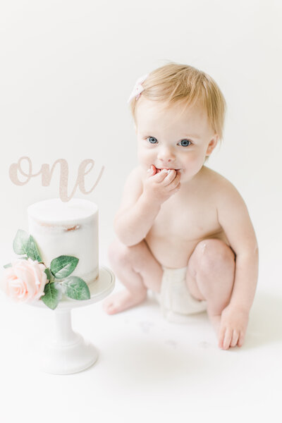 First birthday cake smash with flower cake in white studio.