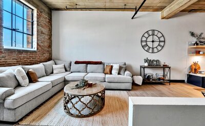 Living room with ample seating and exposed brick in this three-bedroom, two-bathroom industrial modern loft condo in the historic Behrens building in downtown Waco, TX.