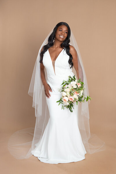 Bride wearing a long chapel length veil with small pearls, and holding a bouquet